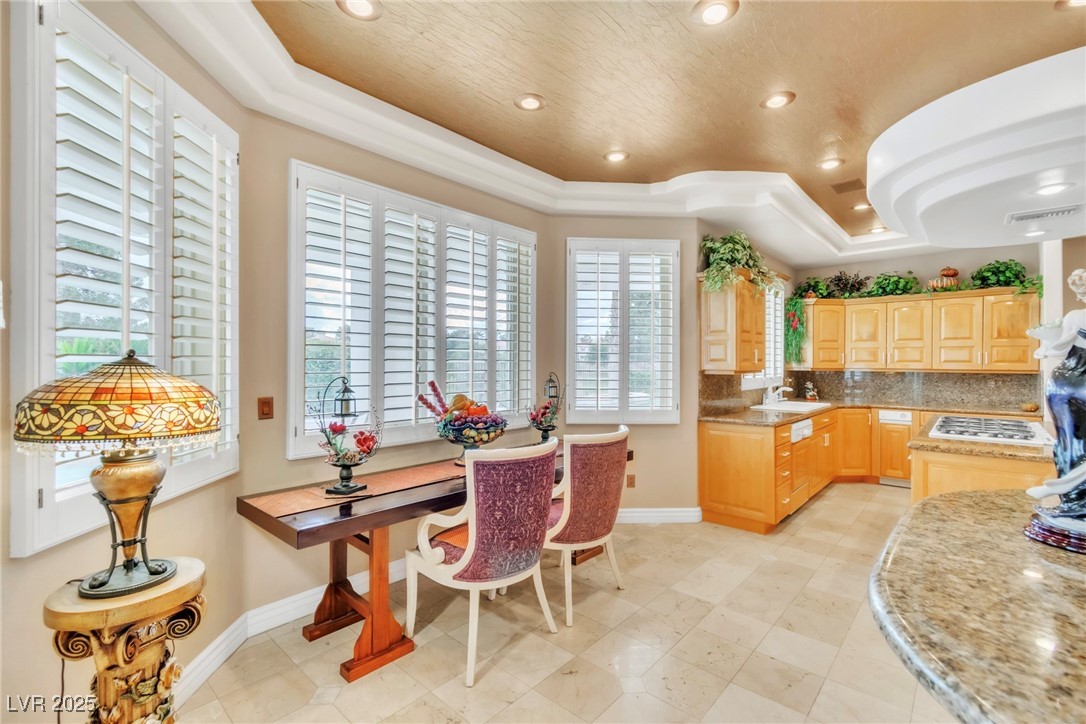 23 Cascade Creek Lane Las Vegas, NV 89113 - Photo 54 of 89 Kitchen featuring light brown cabinets, a raised ceiling, backsplash, recessed lighting, and light stone countertops