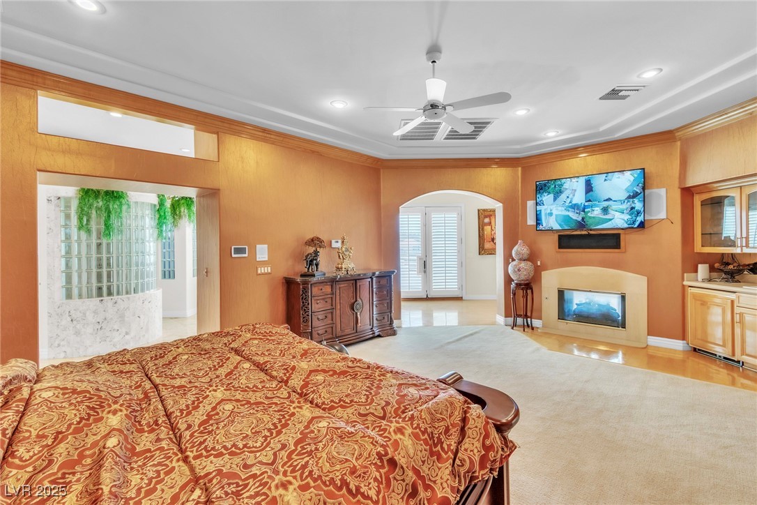 23 Cascade Creek Lane Las Vegas, NV 89113 - Photo 74 of 89 Bedroom with recessed lighting, arched walkways, crown molding, ceiling fan, and a glass covered fireplace