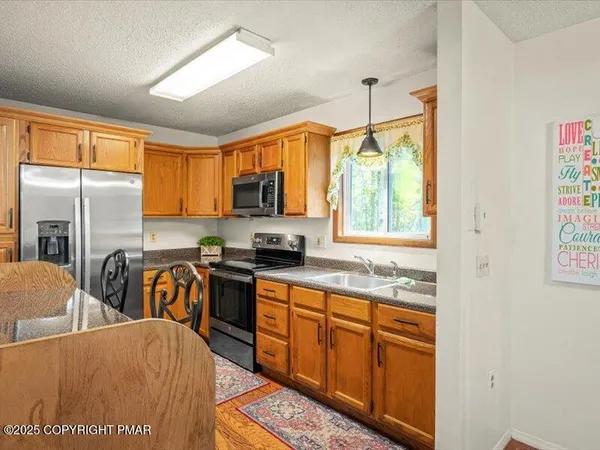 a kitchen with stainless steel appliances granite countertop a refrigerator a sink dishwasher a stove and white countertops with wooden floor