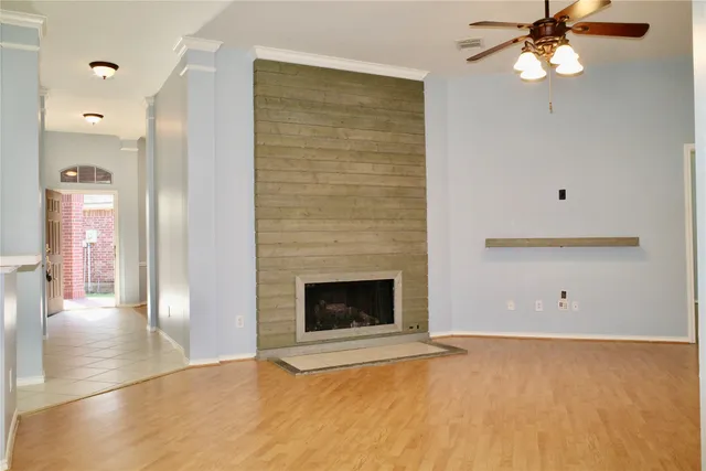 a view of an empty room with chandelier fan and fire place