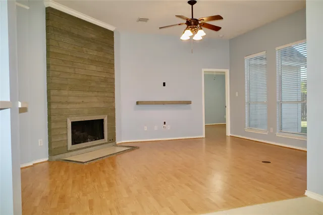 a view of an empty room with chandelier fan and fire place