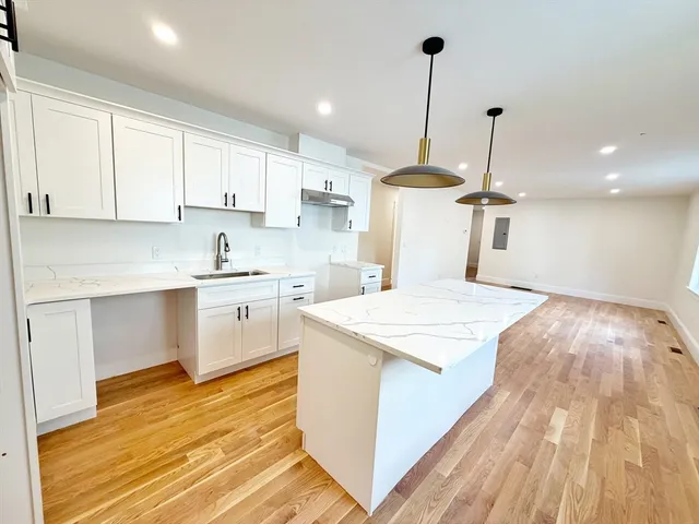 a kitchen with a sink a stove cabinets and wooden floor