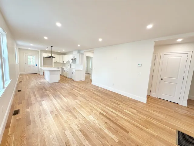 a view of a kitchen with kitchen island wooden floors wooden cabinets counter space and a sink