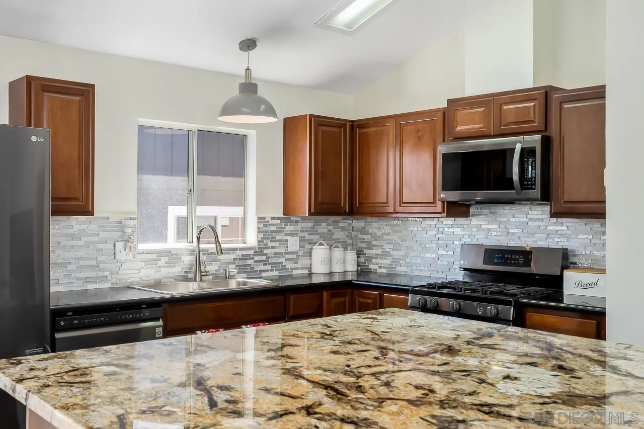 15935 Spring Oaks Road, Unit 201 El Cajon, CA 92021 - Photo 16 of 32 a kitchen with granite countertop wooden cabinets and stainless steel appliances