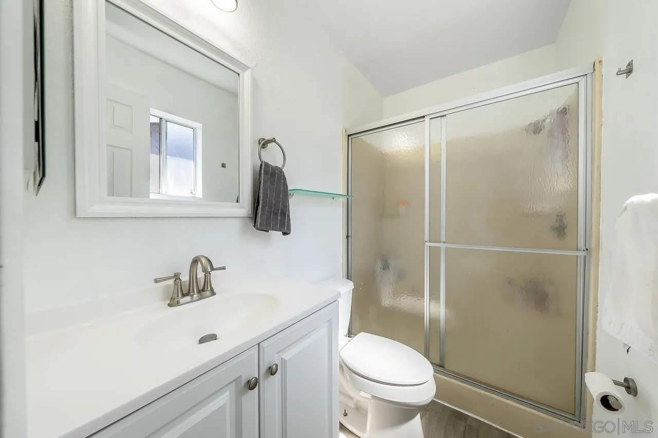 15935 Spring Oaks Road, Unit 201 El Cajon, CA 92021 - Photo 24 of 32 a bathroom with a sink a mirror a toilet and shower