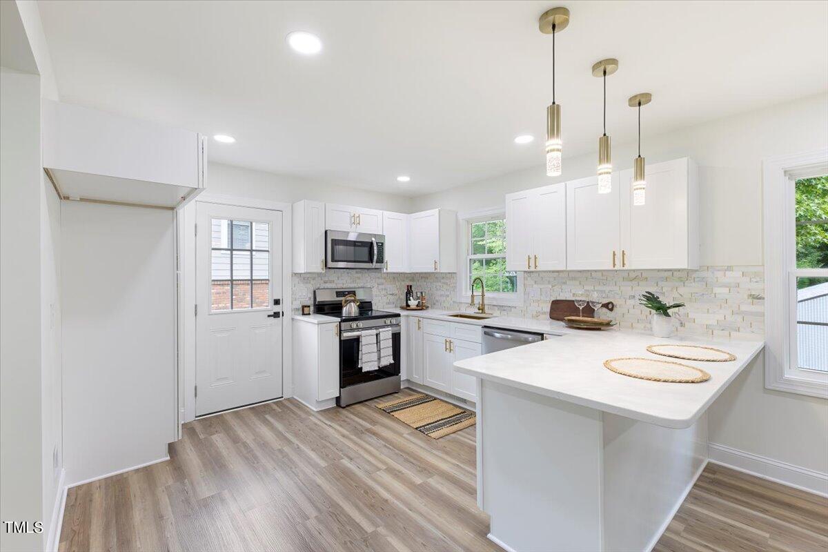 3420 Brentwood Road Raleigh, NC 27604 - Photo 14 of 53 a kitchen with refrigerator a stove and white cabinets with wooden floor