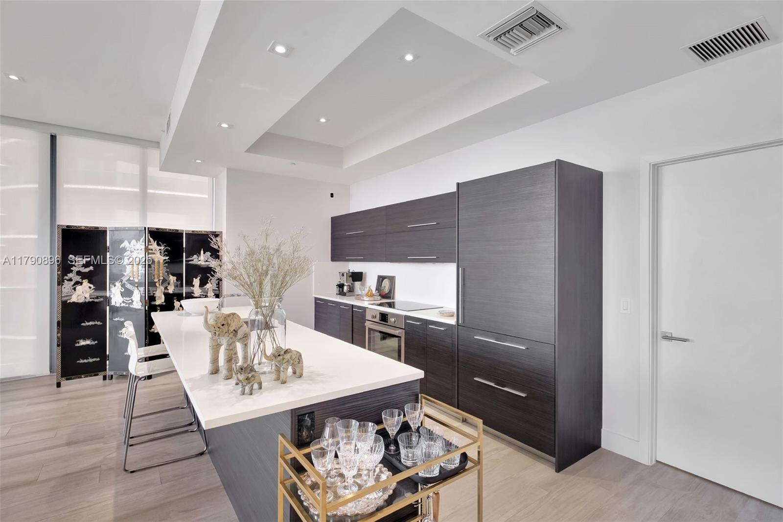 55 Southwest 9th Street, Unit PH4501 Miami, FL 33130 - Photo 15 of 71 a kitchen with stainless steel appliances kitchen island granite countertop a refrigerator a stove a sink a dining table and chairs with wooden floor