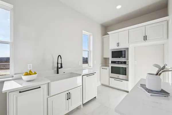 a kitchen with stainless steel appliances a sink a stove and white cabinets