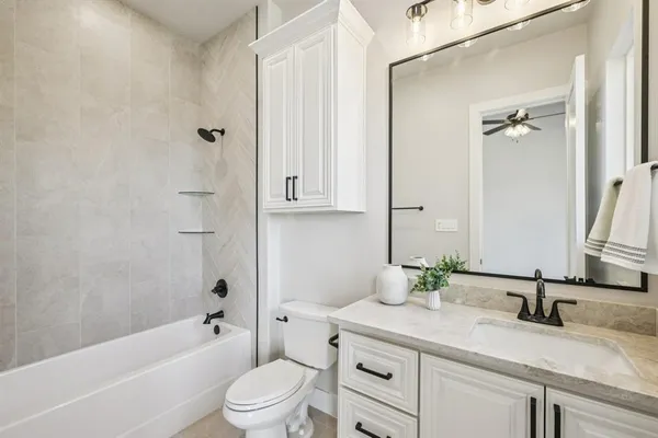 a bathroom with a granite countertop sink a toilet and a bathtub