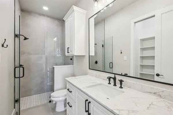a bathroom with a granite countertop sink a toilet and shower