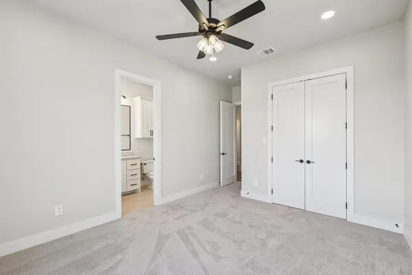 an empty room with closet and a ceiling fan