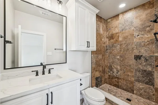 a bathroom with a sink a toilet and shower