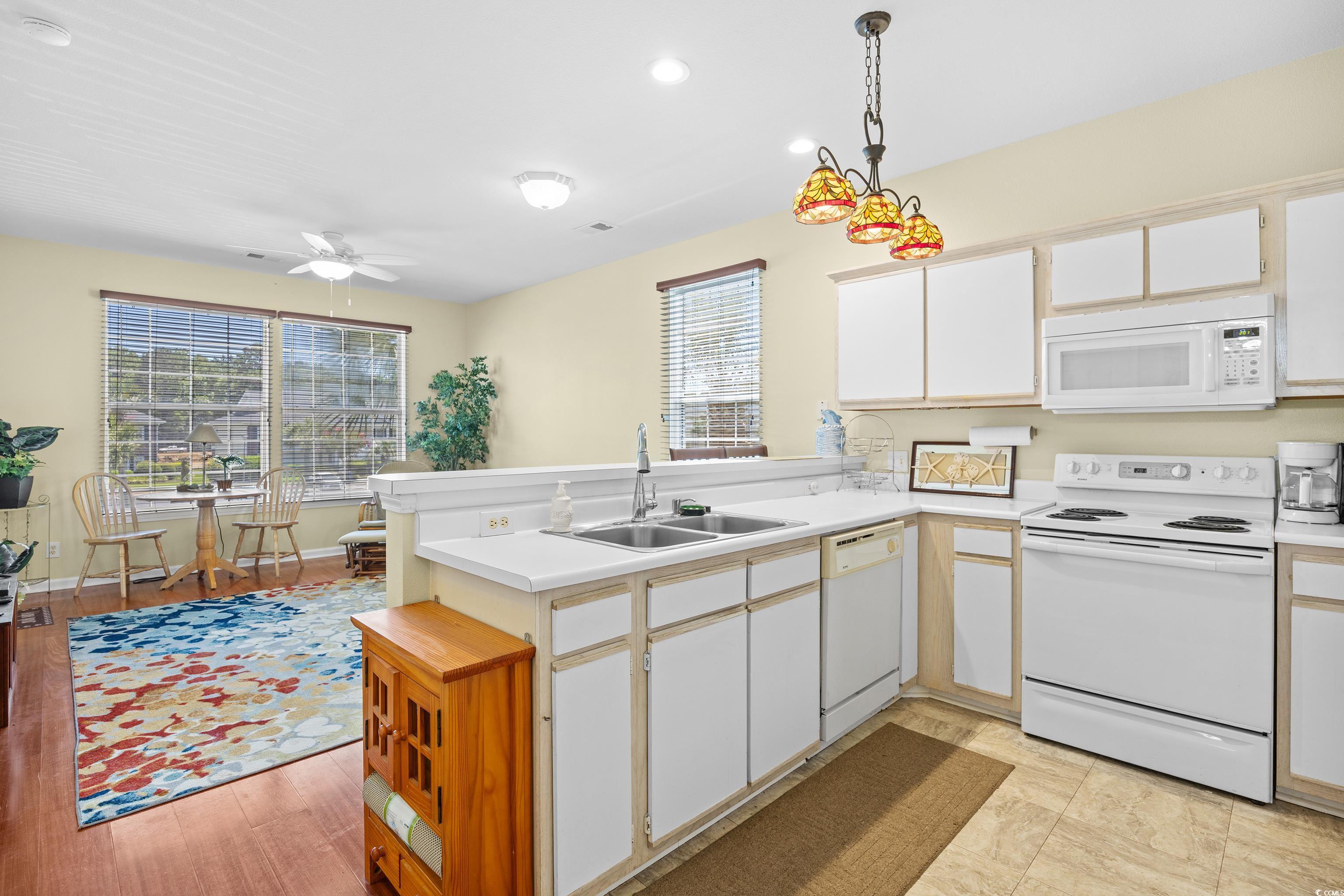1298 River Oaks Drive, Unit 5J Myrtle Beach, SC 29579 - Photo 7 of 33 Kitchen featuring white appliances, a peninsula, light countertops, ceiling fan, and white cabinetry
