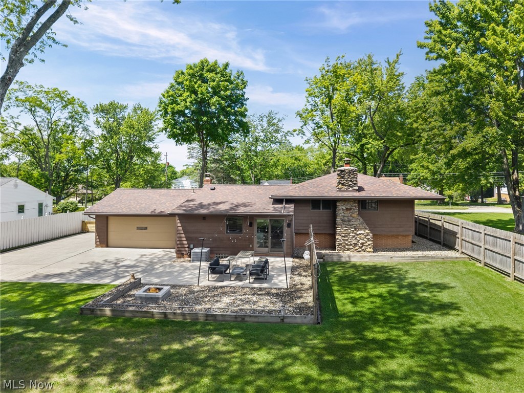 17583 Shurmer Road Strongsville, OH 44136 - Photo 47 of 50 Expansive backyard featuring a stone-clad chimney, a multi-level patio with a fire pit, and a manicured lawn