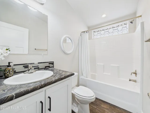 a bathroom with a granite countertop sink mirror vanity and toilet