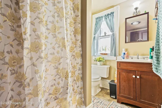 a bathroom with a granite countertop sink and a toilet