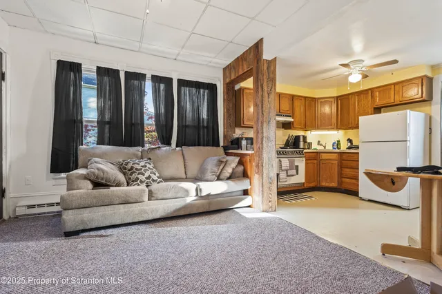 a living room with stainless steel appliances furniture windows and a kitchen view