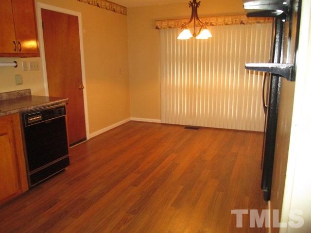 704 Cooper Road Raleigh, NC 27610 - Photo 8 of 25 an empty room with wooden floor windows and a fireplace