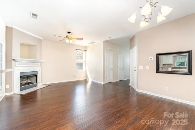 an empty room with wooden floor fireplace and windows