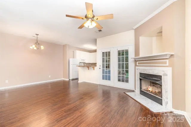 a view of an empty room with wooden floor fireplace and a window