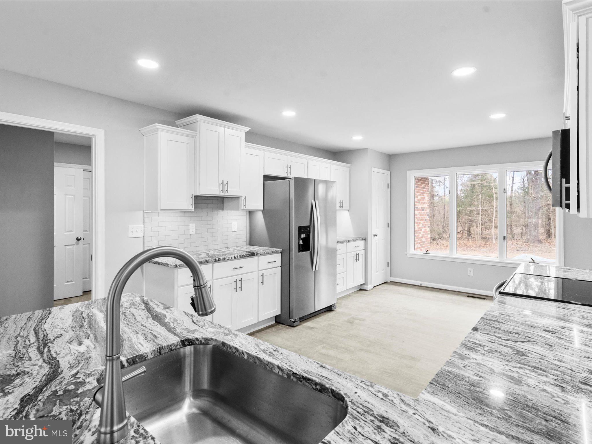 10009 River Road Petersburg, VA 23803 - Photo 18 of 59 a large kitchen with stainless steel appliances granite countertop a stove a sink a refrigerator and white cabinets with wooden floor