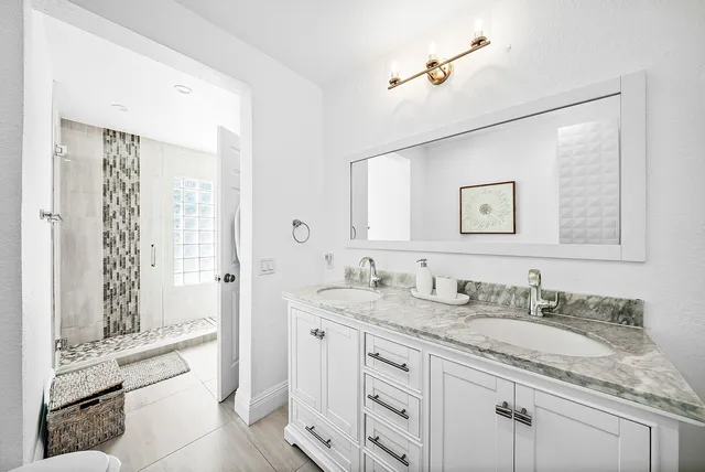 a bathroom with a granite countertop sink a mirror a vanity and a bathtub