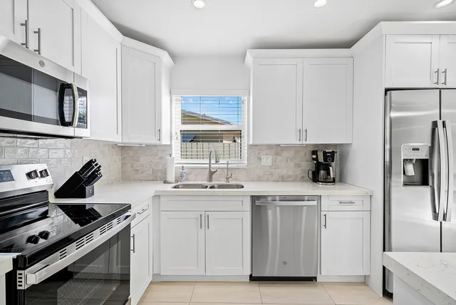 a kitchen with white cabinets stainless steel appliances and sink