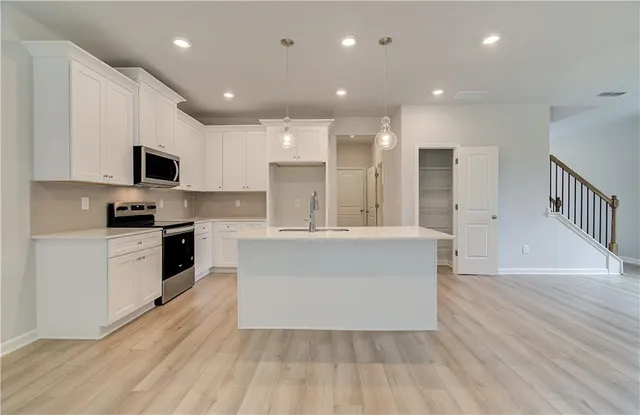 a large kitchen with stainless steel appliances a large counter top a stove a microwave and a refrigerator