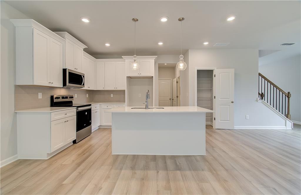 84 Hydrangea Circle Fairburn, GA 30213 - Photo 11 of 23 a large kitchen with stainless steel appliances a large counter top a stove a microwave and a refrigerator