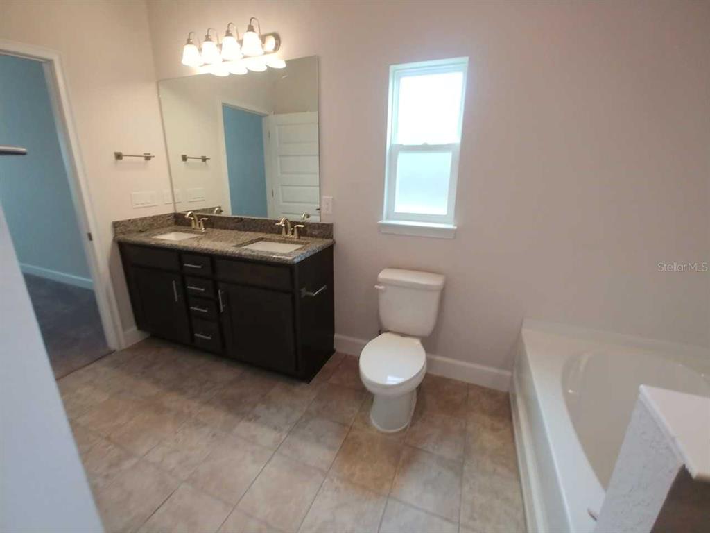 4380 Southwest 92nd Pl Road Ocala, FL 34476 - Photo 23 of 57 a bathroom with a granite countertop toilet sink and mirror