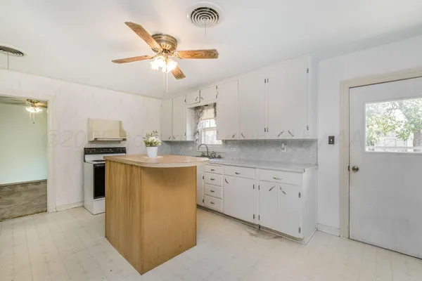 a kitchen with granite countertop a refrigerator a sink dishwasher a stove and white cabinets with wooden floor