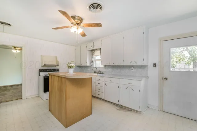 a kitchen with granite countertop a refrigerator a sink dishwasher a stove and white cabinets with wooden floor