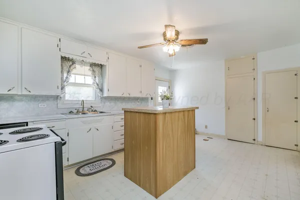 a kitchen with a refrigerator a sink and dishwasher a stove top oven with white cabinets