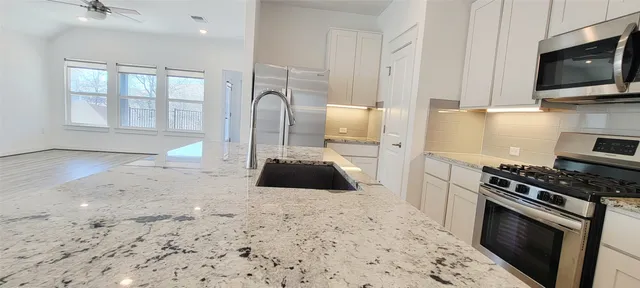 a kitchen with granite countertop white cabinets and white appliances