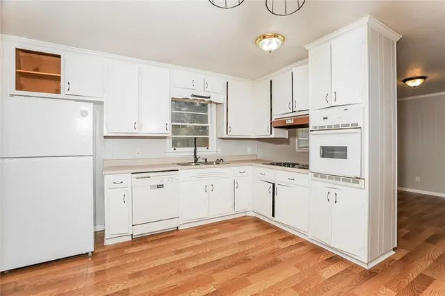 a kitchen with granite countertop white cabinets and white appliances