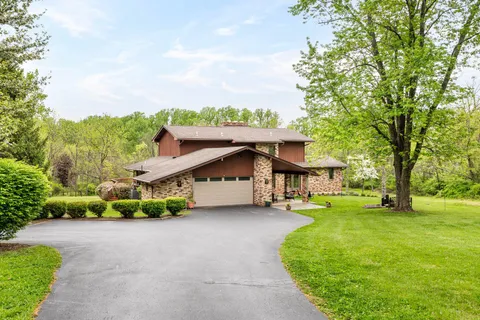 a view of a house with a big yard and large trees