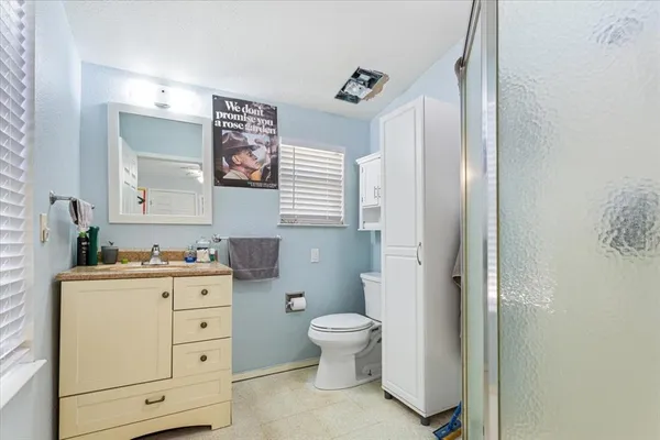 a bathroom with a toilet a sink a mirror a vanity and window