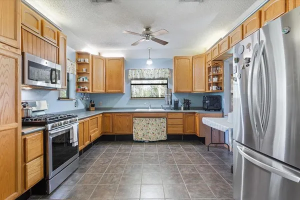 a kitchen with stainless steel appliances granite countertop a refrigerator a sink dishwasher a stove and white cabinets with wooden floor