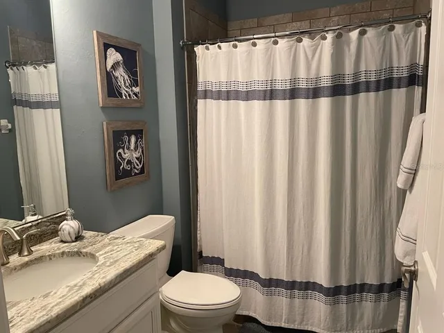 a bathroom with a granite countertop sink toilet and shower