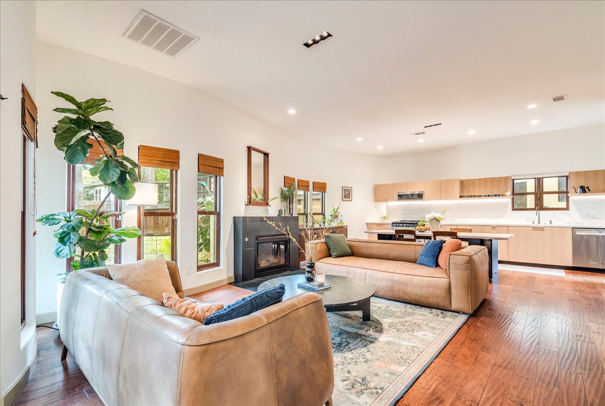 3012 South 4th Street, Unit B Austin, TX 78704 - Photo 3 of 40 Open-concept living space featuring wood-finish flooring, a contemporary fireplace with dark stone surround, recessed lighting, and large windows
