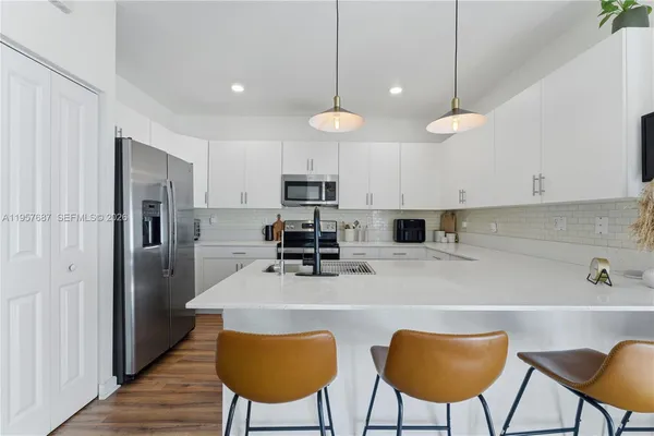 a kitchen with stainless steel appliances a table chairs refrigerator and microwave