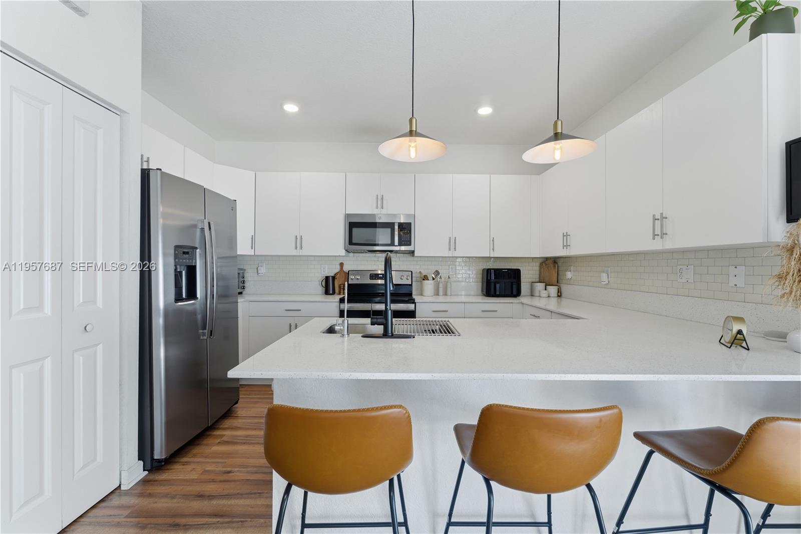 11456 West 33rd Way Hialeah, FL 33018 - Photo 12 of 49 a kitchen with stainless steel appliances a table chairs refrigerator and microwave