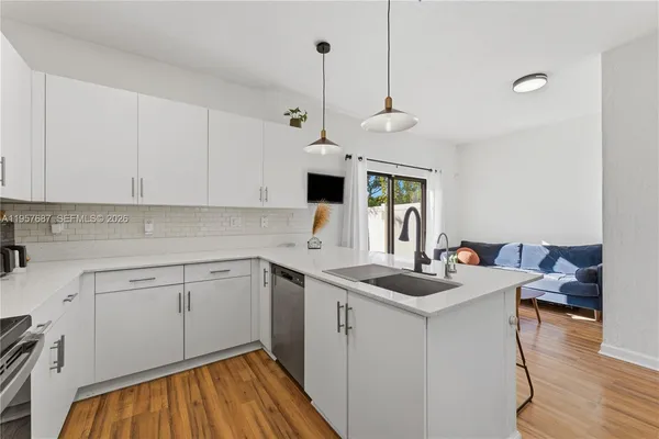 a kitchen that has a cabinets a sink and a stove with wooden floor