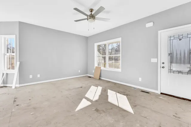 an empty room with windows and ceiling fan