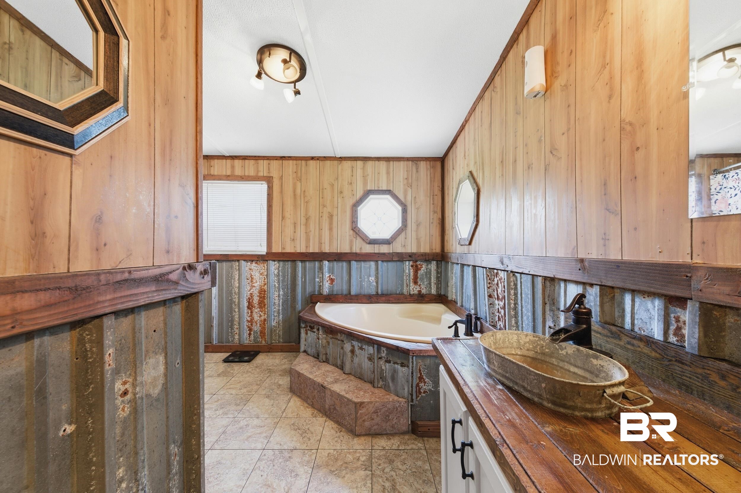 926 Tumbling Lane Atmore, AL 36502 - Photo 30 of 56 Bathroom featuring a corner soaking tub with stepped access, wood-finish paneling, and corrugated metal wainscoting