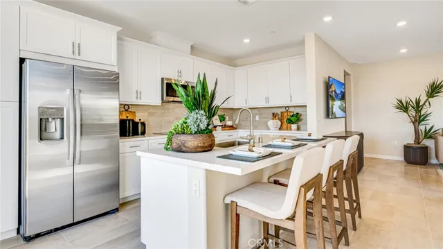 a kitchen with stainless steel appliances kitchen island a table in it and white cabinets