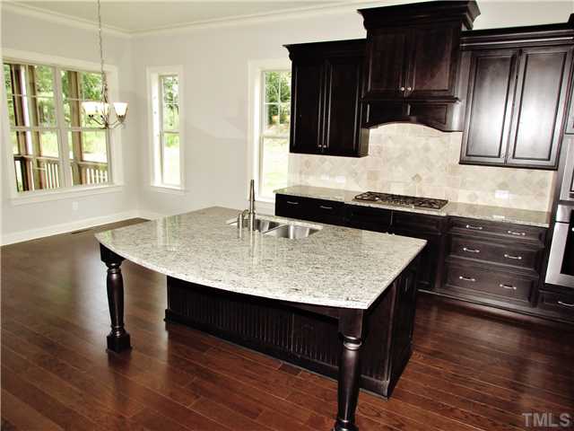 3204 Bryant Falls Court, Unit LOT58 Raleigh, NC 27613 - Photo 8 of 25 a view of kitchen island with granite countertop wooden cabinets and wooden floor