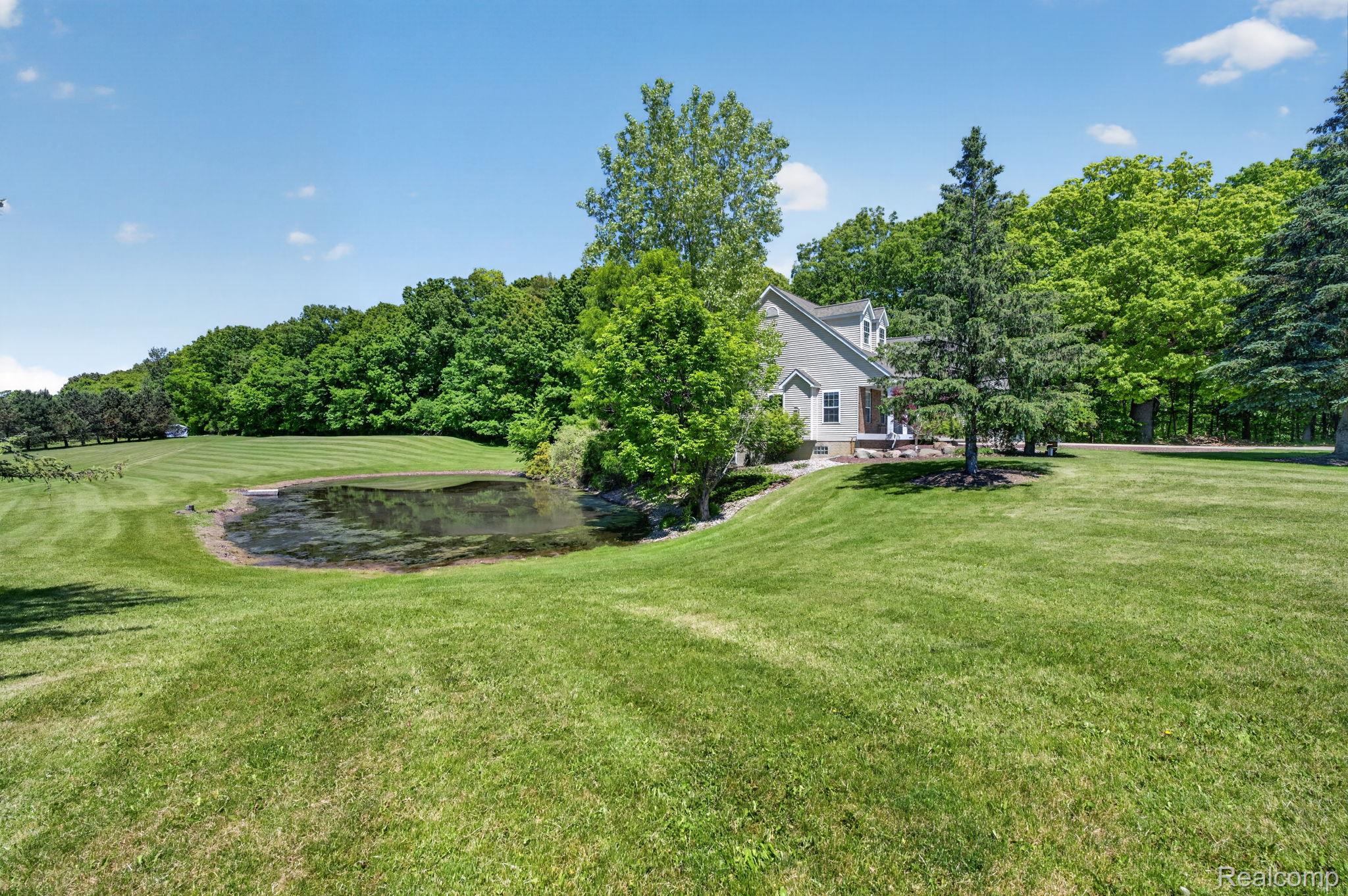9055 Hegel Road Grand Blanc, MI 48439 - Photo 6 of 62 Expansive green lawn featuring a natural pond and mature trees