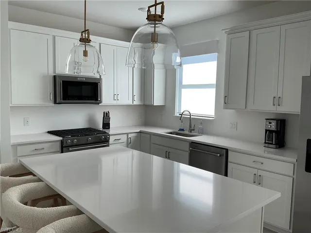 a large kitchen with a table chairs refrigerator and cabinets