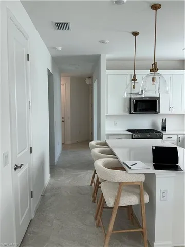 a kitchen with stainless steel appliances a stove a sink a microwave a refrigerator white cabinets and a window